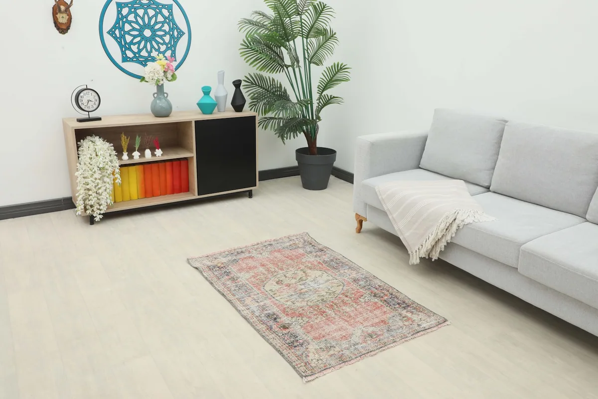 Vintage rug displayed in a living room setting with a light gray couch and wooden cabinet