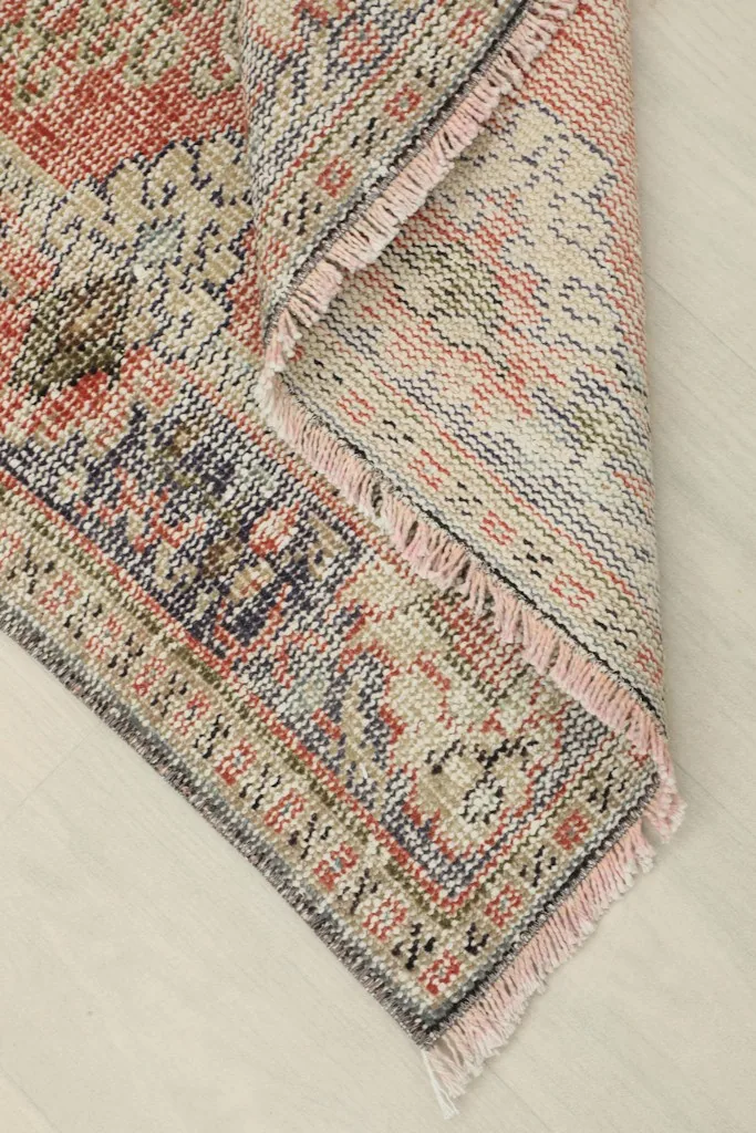 Corner of the rug folded to show the cotton foundation and hand-knotted construction