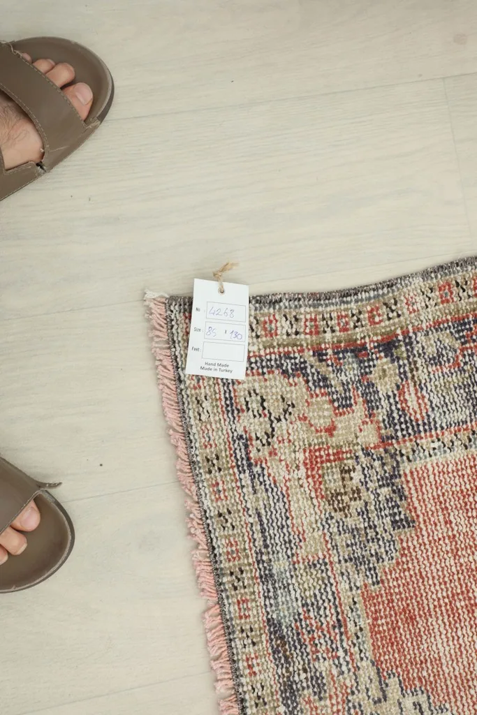 Corner of the rug with a tag, next to feet for scale