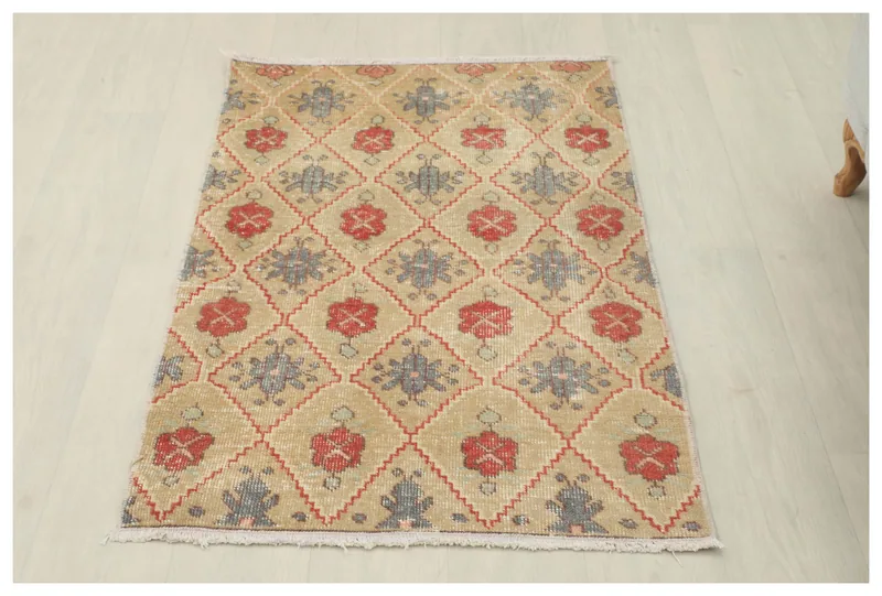 Full overhead view of the tan, red, and gray geometric vintage area rug on a white floor.