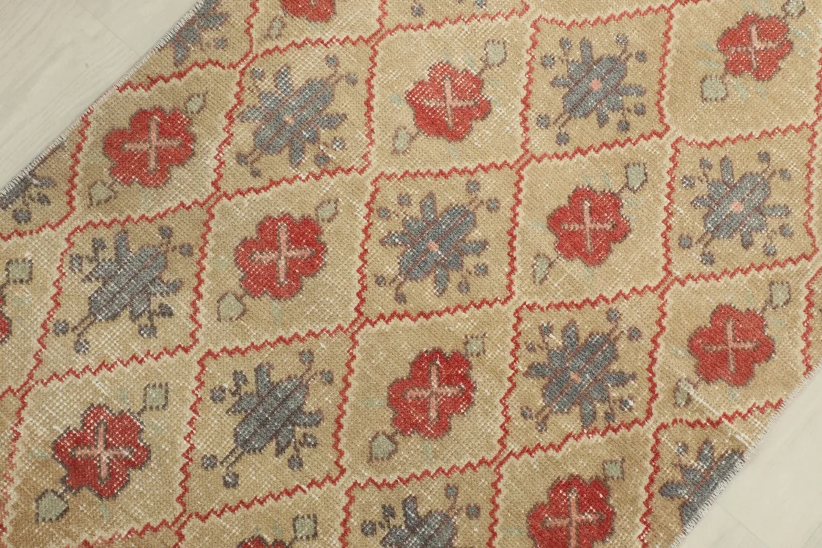 Detailed view of the geometric pattern, highlighting the red and gray elements on the tan background.