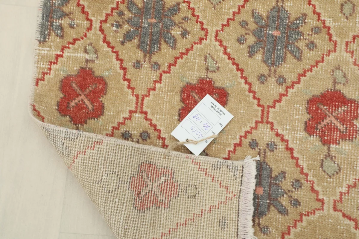 Partial view of the rug's backside, showing its construction and a tag attached to the corner.
