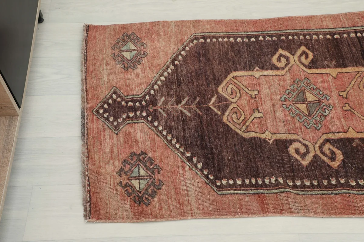 Opposite end close-up angle of the runner rug, showing the rust field and brown medallion.
