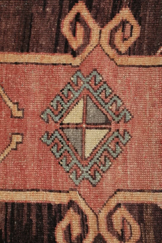 Close-up of a central geometric motif within a brown medallion, showing color variations.