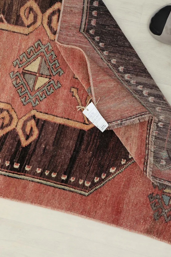 Detail of the rug's reverse side and a tag, showing the hand-knotted construction.