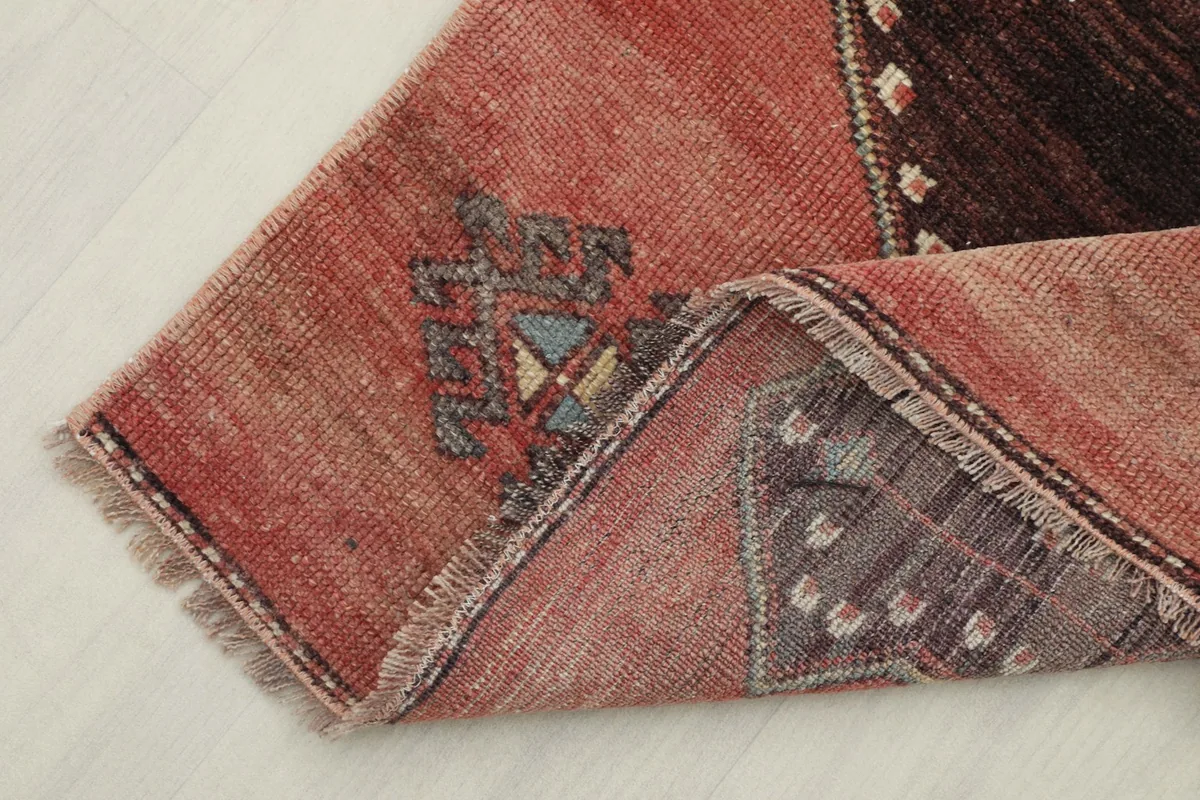 Folded corner of the runner rug, revealing the wool pile and cotton foundation.