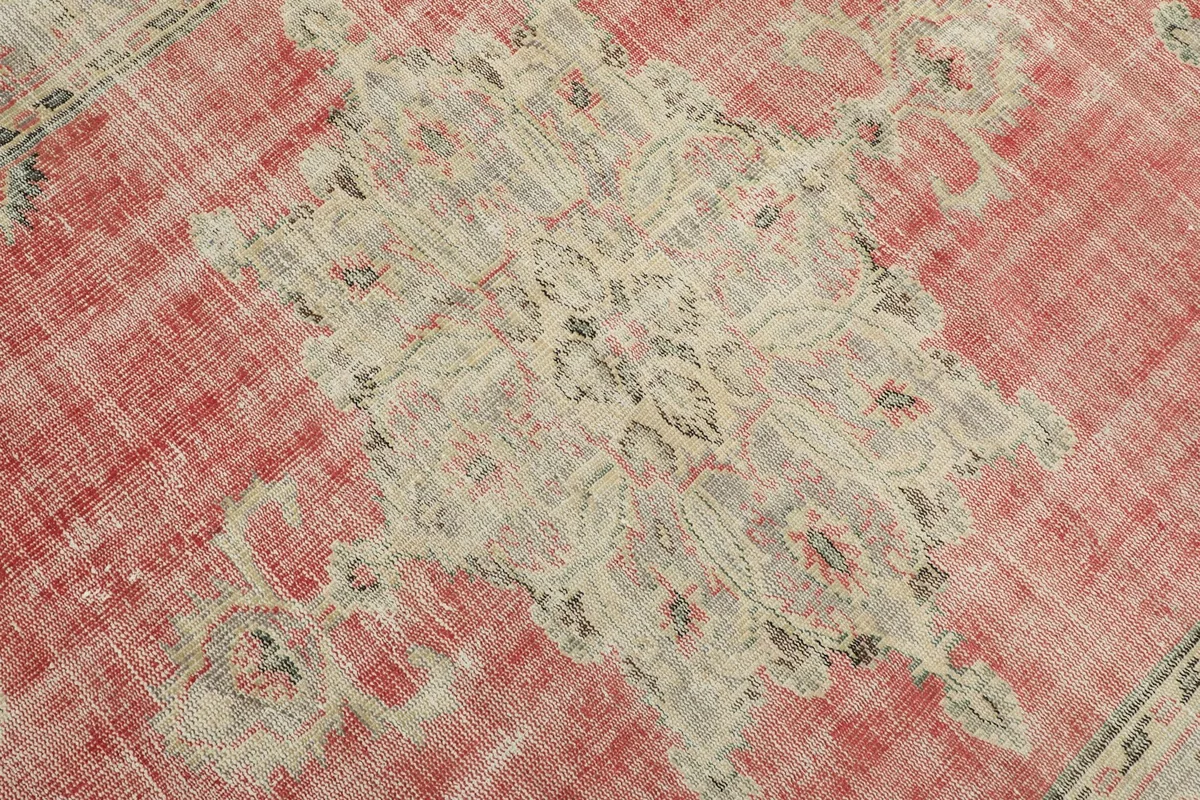 Detailed view of the central medallion design on the rose field, showing faded colors