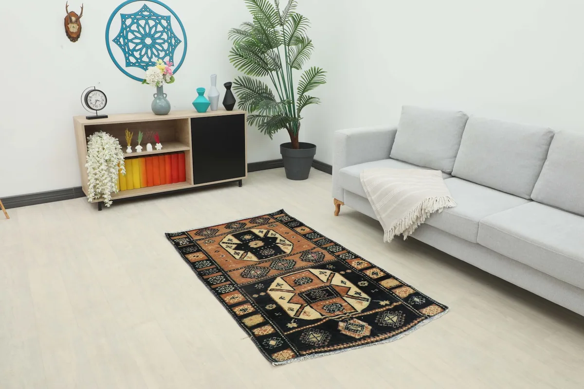 Vintage Anatolian rug with black and rust colors placed in a modern living room setting.