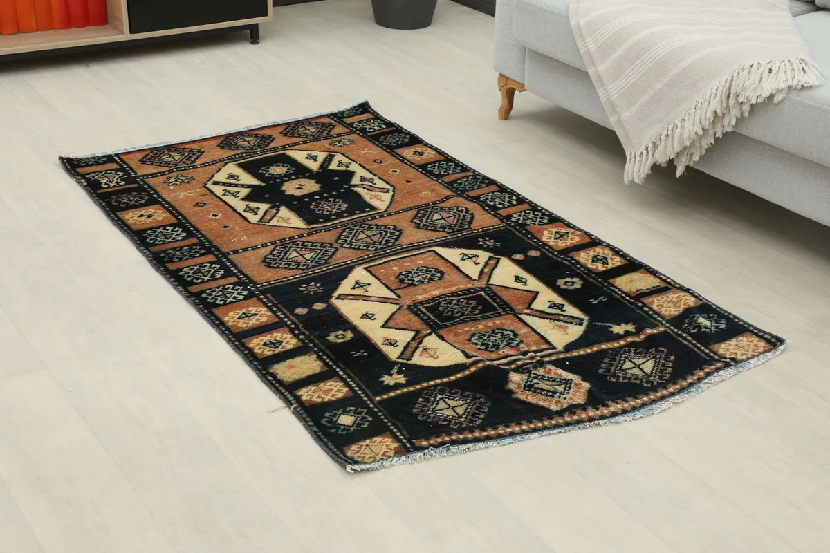 Angle view of the black and rust geometric rug in a room, showing its placement beside a sofa.