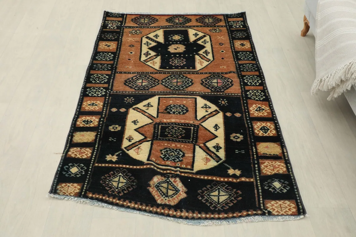 Overhead view of the entire rug, showcasing its full black, rust, and ivory pattern and shape.