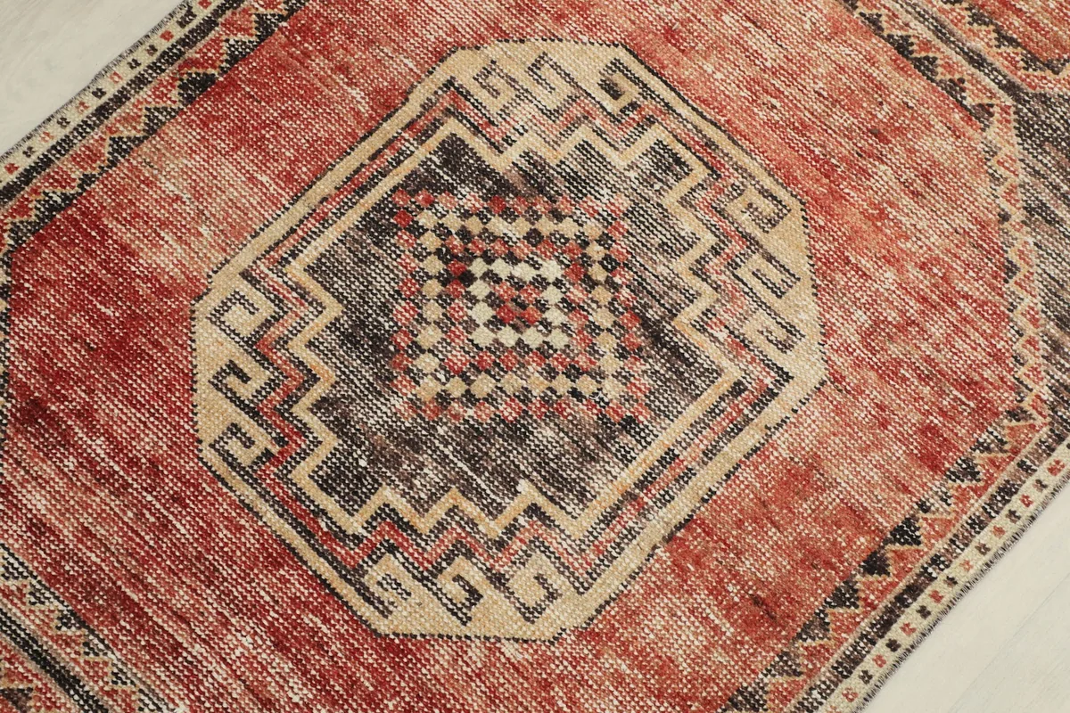 Detailed view of a central octagonal medallion with intricate charcoal and beige tribal patterns.