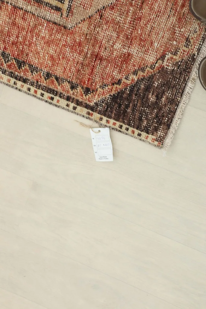 Corner of the rug with a tag, showing the edge and a small section of the pattern.