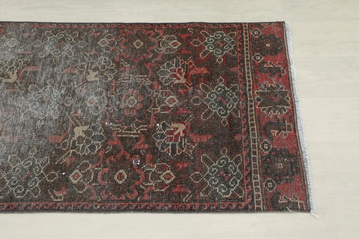 Close-up view of one end of the runner, showing red and charcoal geometric patterns and fringe.