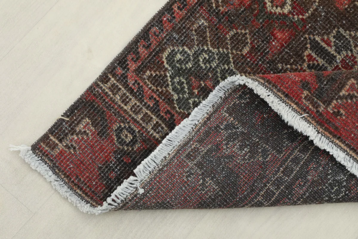 Corner of the rug folded back to reveal the cotton foundation and hand-knotted construction.