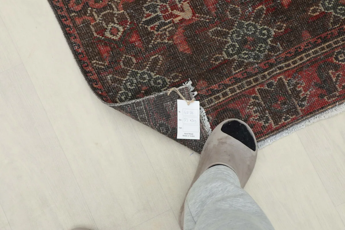 A foot in a slipper next to the folded rug, providing a sense of scale for the runner.