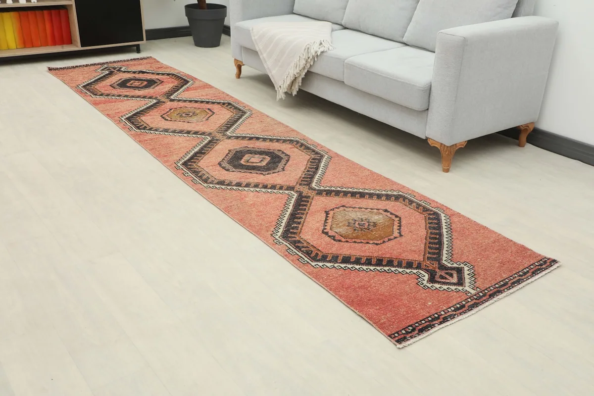 Angled view of the rust runner rug extending from a light gray sofa in a room