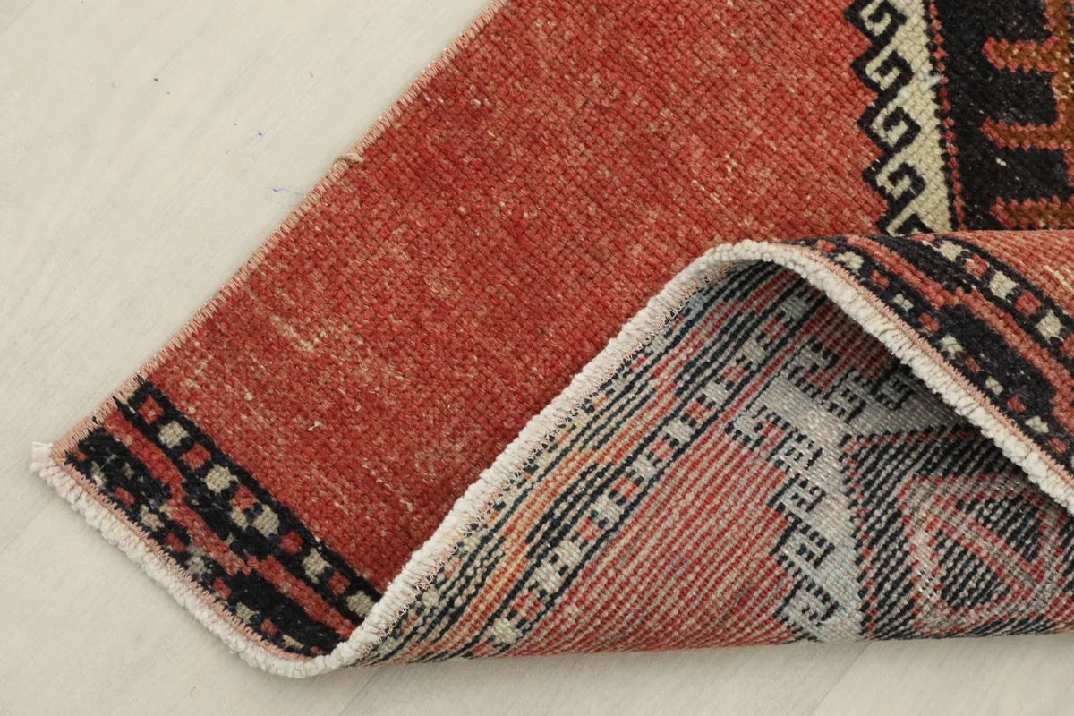 Corner of the rust runner rug folded to show the back and foundation