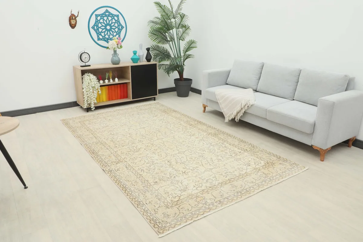 Vintage ivory and gray rug displayed in a living room setting with a light gray sofa and wooden cabinet.