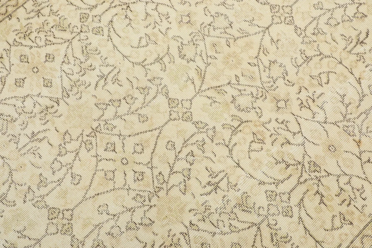 Detailed view of the rug's central field pattern, showing the faded gray and beige motifs on ivory.