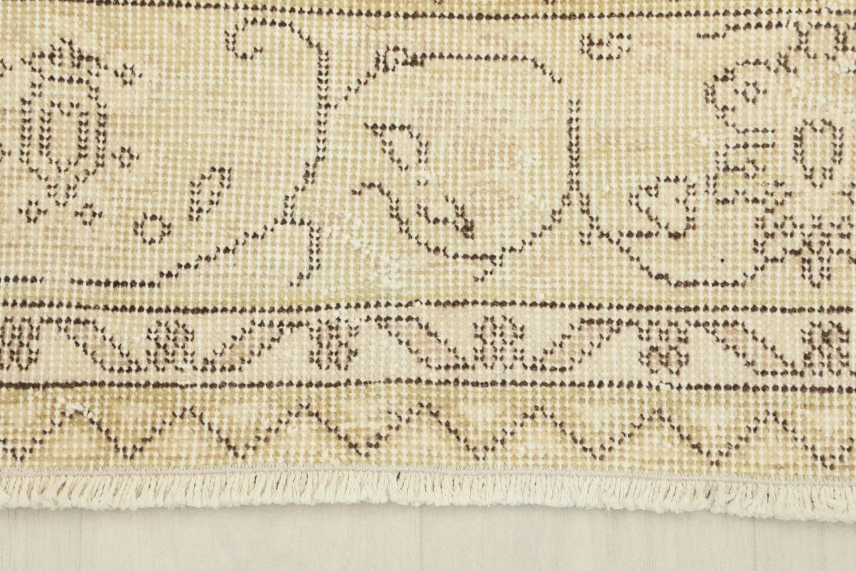 Detail of the rug's border, showcasing the distinct geometric and floral elements and fringe.