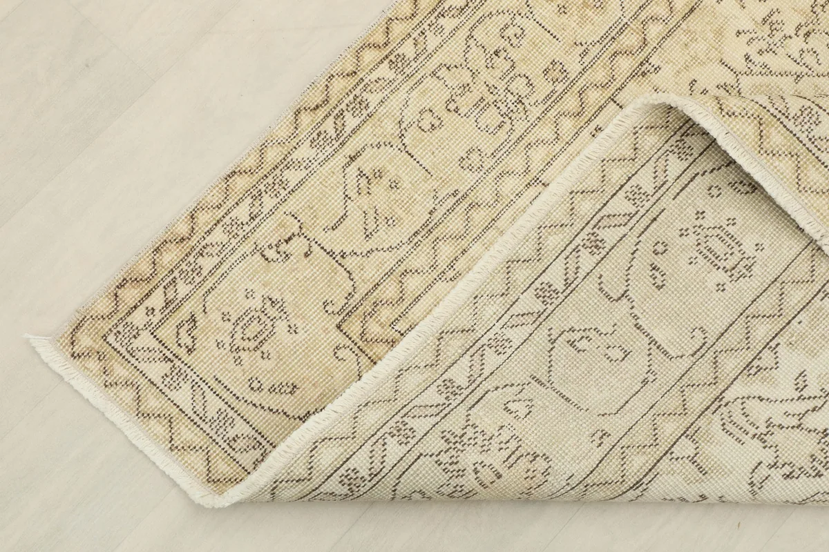 Corner of the rug folded back to show the cotton foundation and hand-knotted construction.