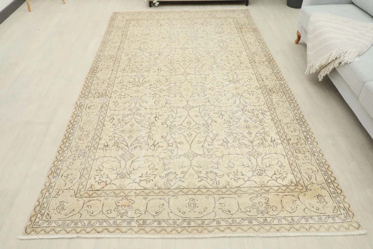 Full overhead view of the vintage ivory rug in a room setting, showing its overall appearance.