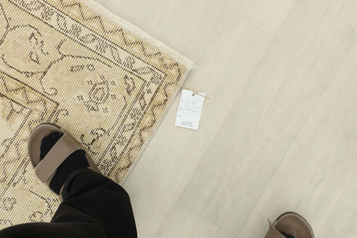 Foot next to the rug's corner, providing a sense of scale and the rug's texture.