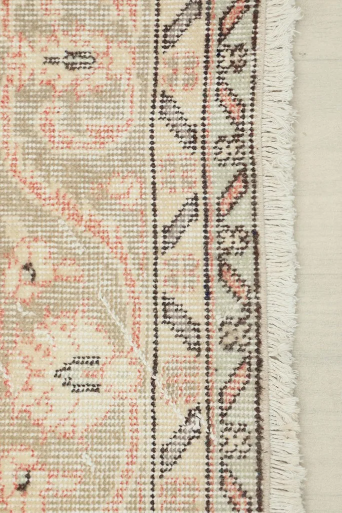 Close-up of the rug's border and fringe, detailing the geometric and floral patterns.