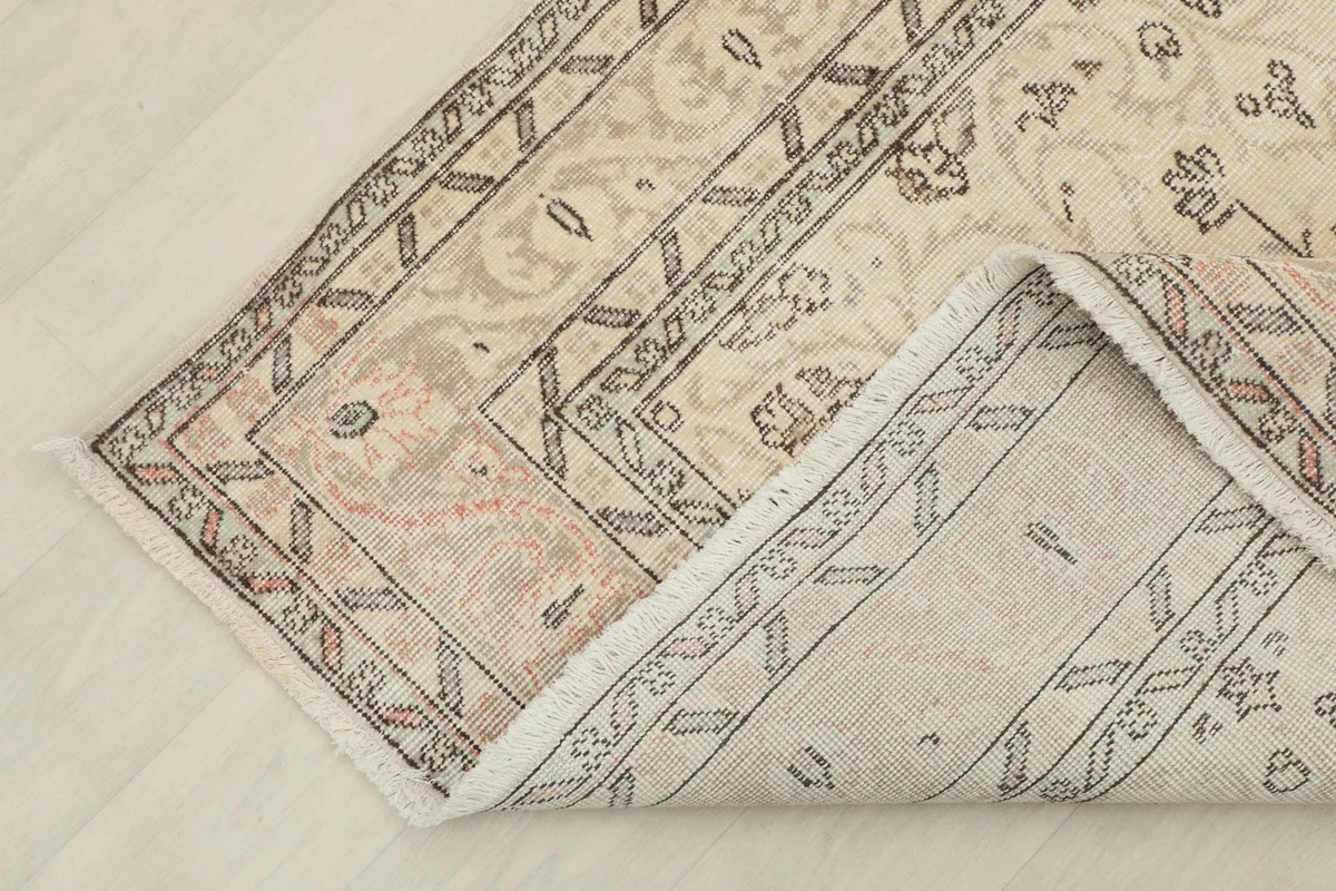 Corner of the rug folded back to reveal the hand-knotted construction and cotton foundation.