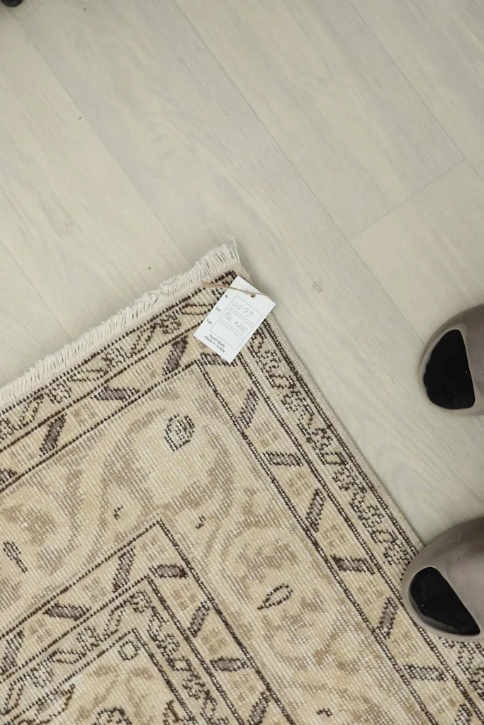 Overhead view of a corner of the rug with the product tag, showing the texture and fringe.