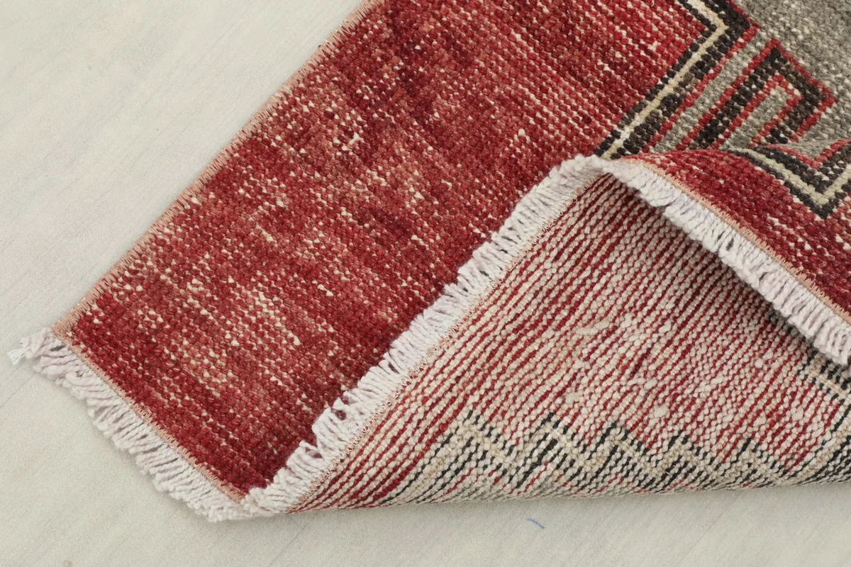 View of the low wool pile and a corner folded to show the hand-knotted construction.
