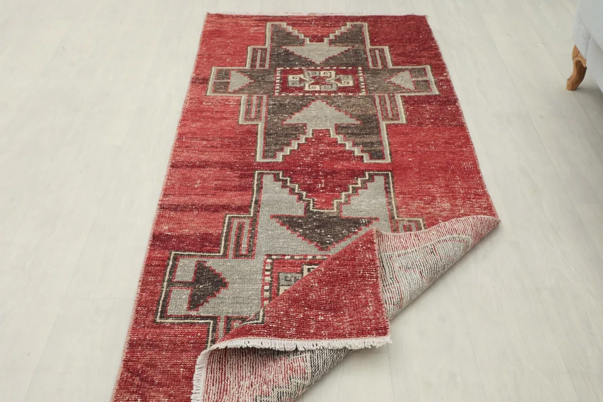 The red runner partially folded back to reveal the cotton foundation and hand-knotted weave.