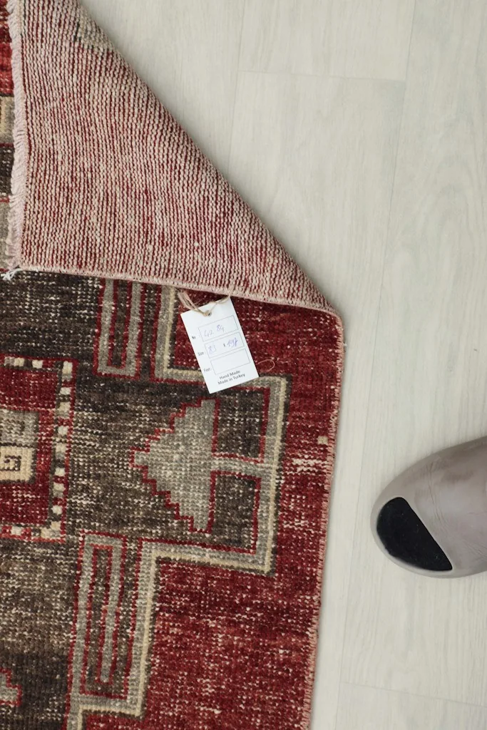 Underside view of the hand-knotted runner, showing the foundation and a product tag.