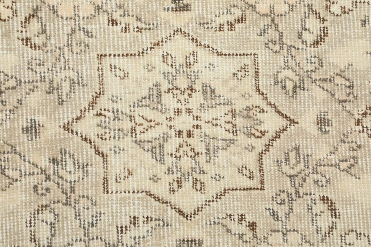 Detailed view of the hand-knotted texture and faded gray patterns on the cream pile