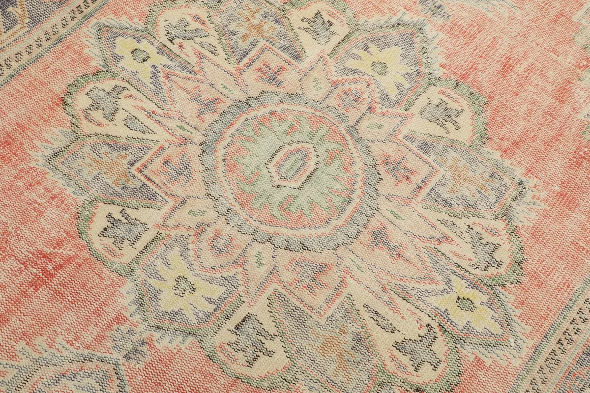 Detailed view of the central medallion design with rust, blue, green, and cream colors