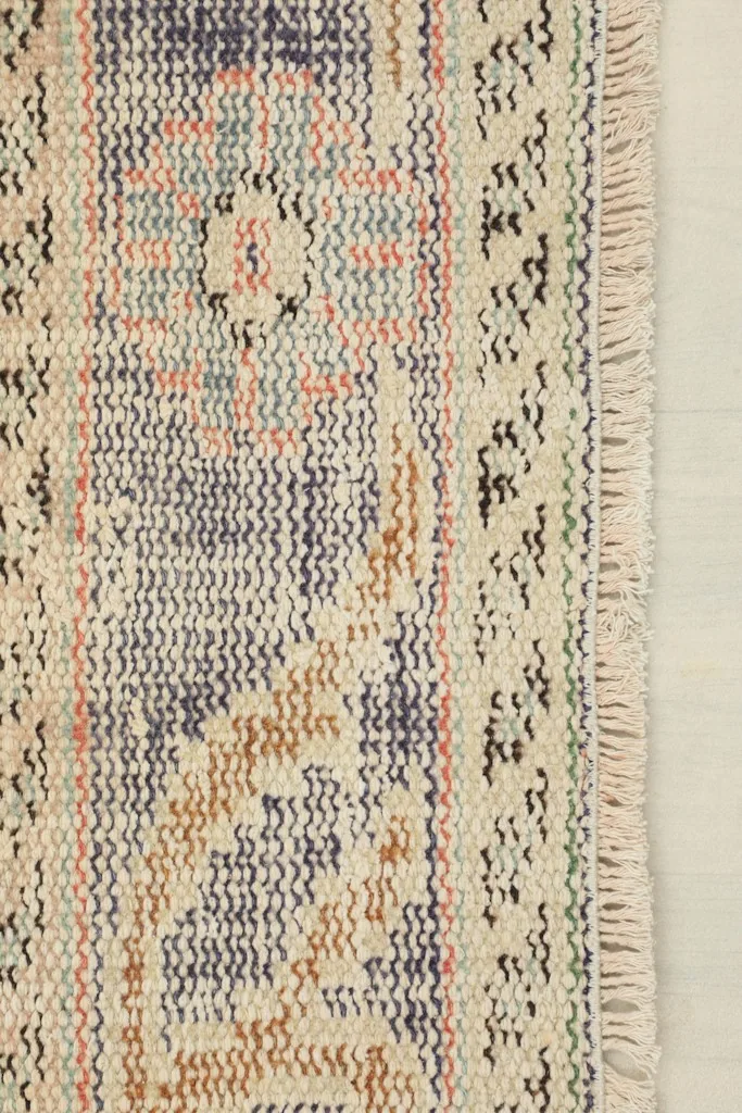 Close-up of the short, natural fringe and the detailed border pattern of the rug