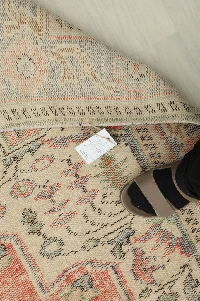 A foot next to the rug showing its scale and the texture of the pile and foundation