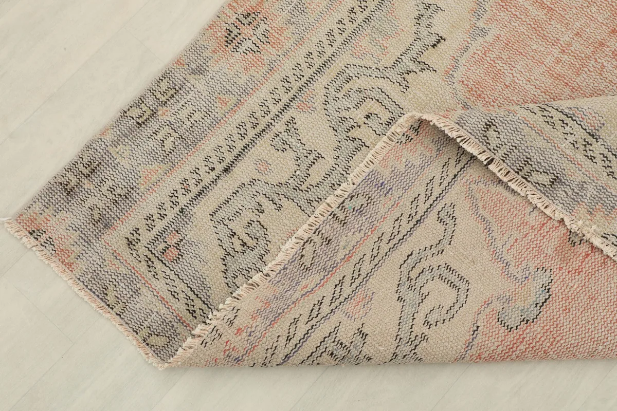 Corner of the rug folded back, showing the wool pile and cotton foundation