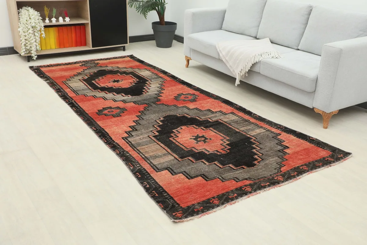 Angle view of the red, gray, and black geometric area rug complementing a contemporary room with a gray sofa.