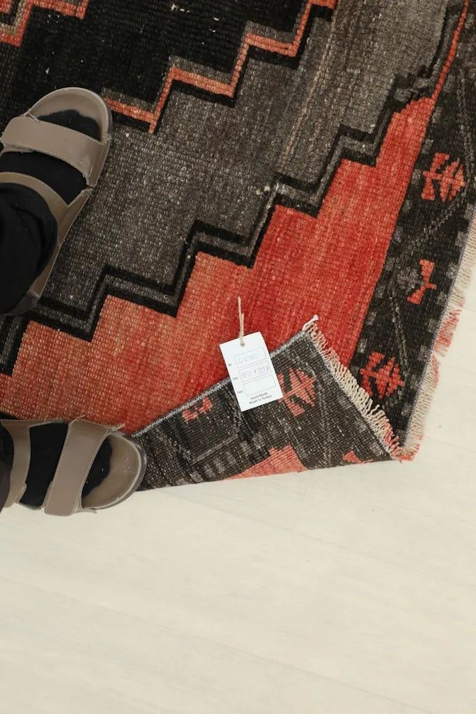 Overhead view of a foot next to the rug's edge, showing the low pile and a product tag.