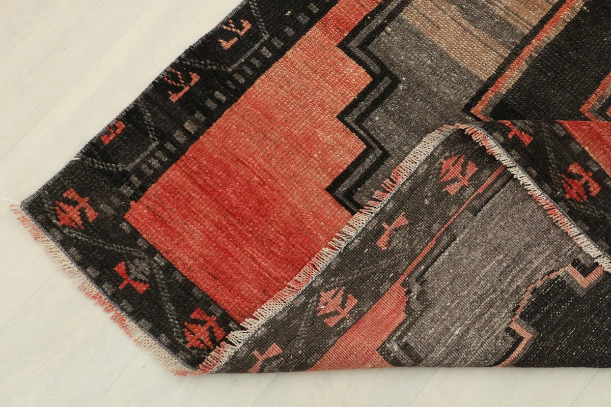 Folded corner of the vintage rug, showing the reverse side and the hand-knotted wool pile.