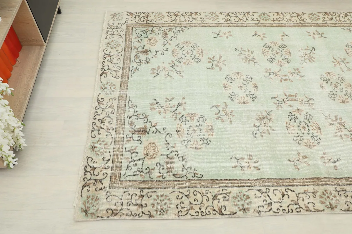 Corner view of the vintage rug, highlighting the intricate floral patterns and beige border.
