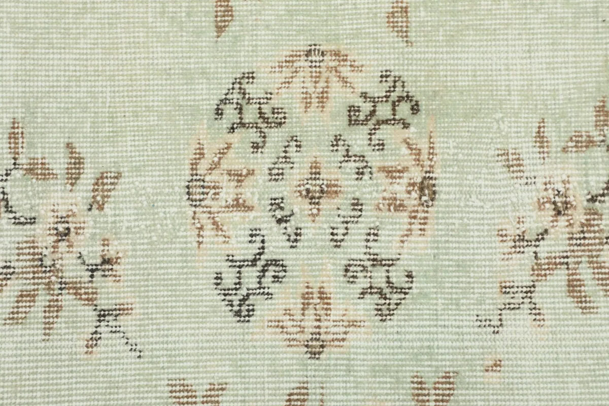 Close-up of a central medallion motif on the rug, showing the faded green and brown wool pile.