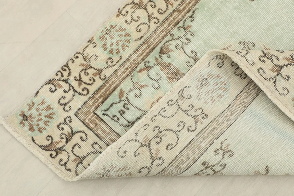 Folded corner of the rug, revealing the cotton foundation and the reverse side of the hand-knotted construction.