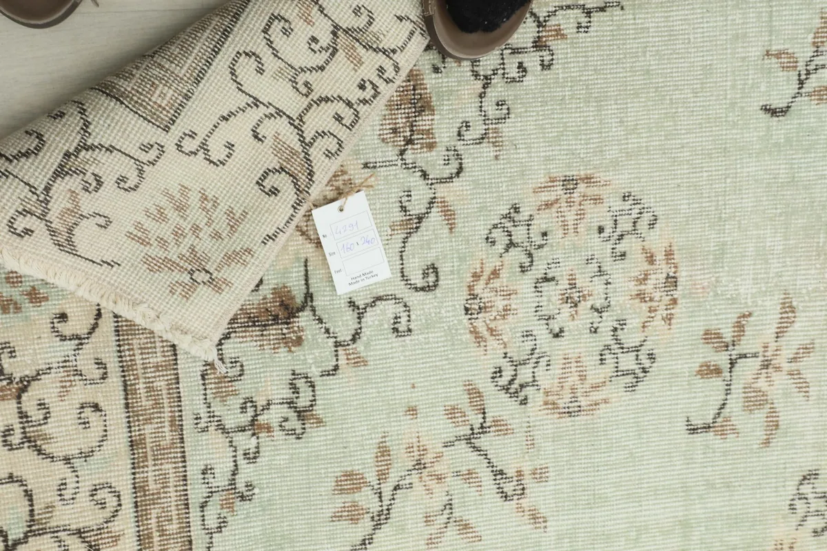 Overhead view showing the rug's texture, a small tag, and a person's feet, indicating scale.