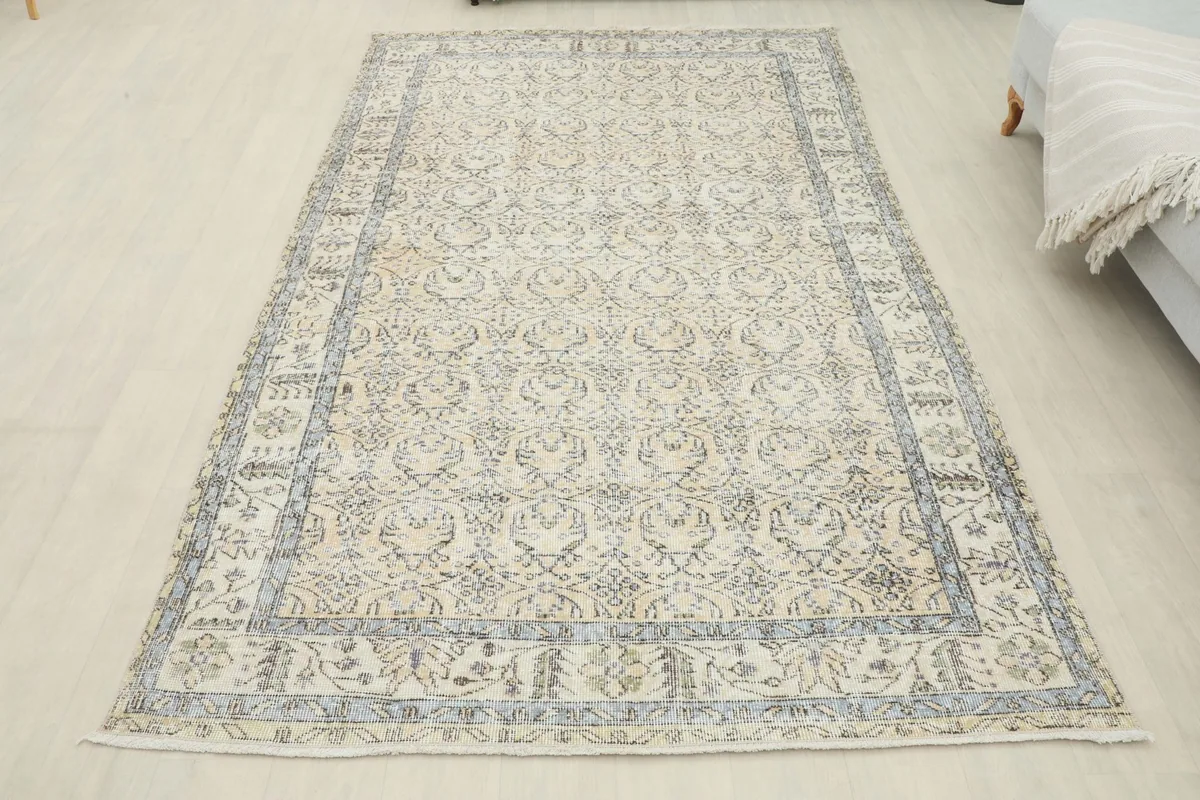 Full overhead view of the 5'1" x 8'10" ivory and charcoal vintage Anatolian area rug in a room.