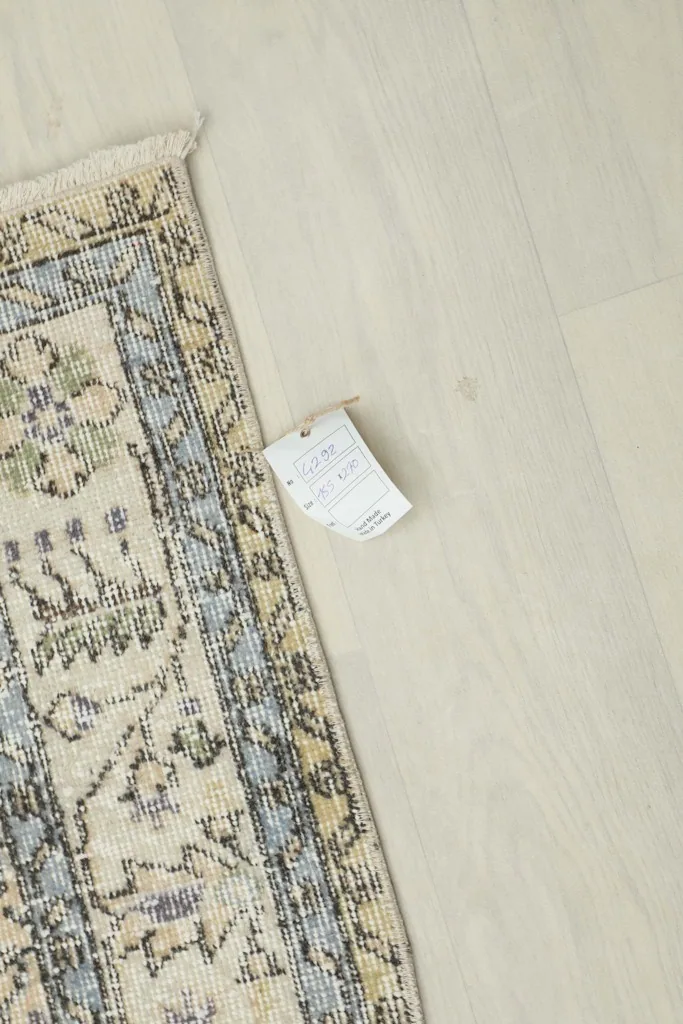 Corner of the rug with a product tag, displaying information about its origin and material.
