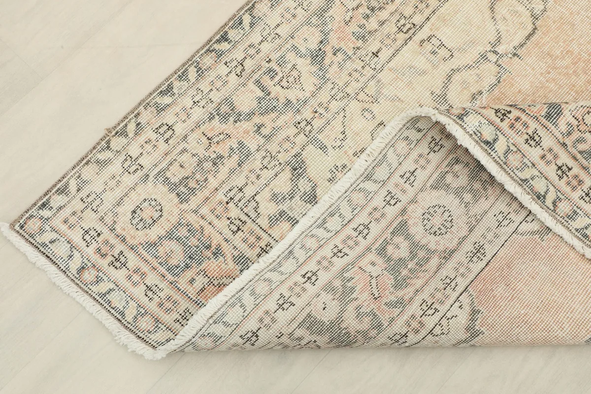 Corner of the rug folded back, revealing the reverse side of the hand-knotted cotton foundation.