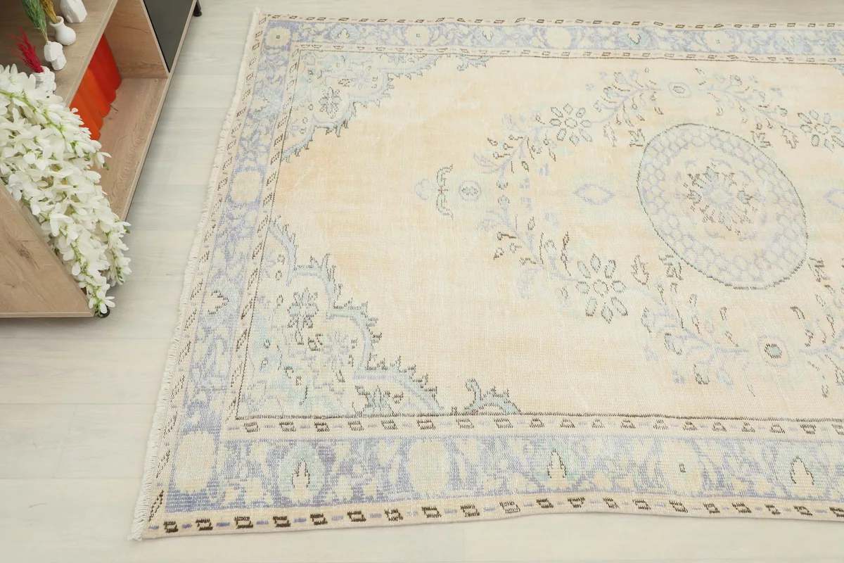 Angled view highlighting the soft ivory field and intricate blue floral motifs