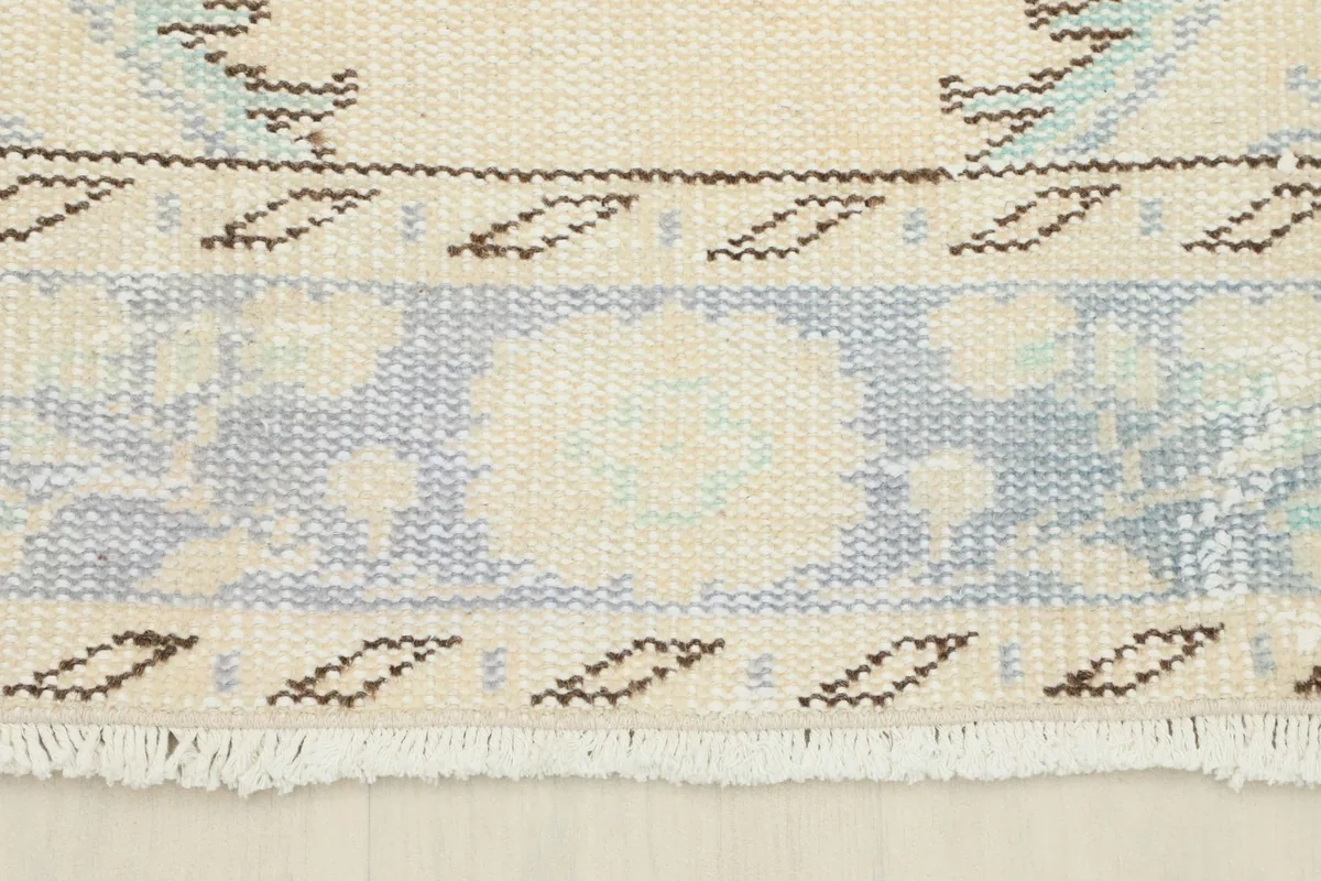 Close-up of the rug's short, natural ivory fringe and border design